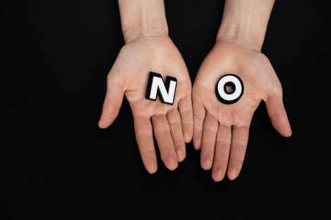 Letter tiles spelling 'NO' in two open hands
