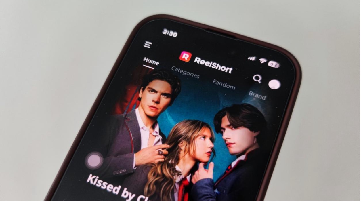 Phone screen on a white background. The phonescreen is showing two men and one woman.